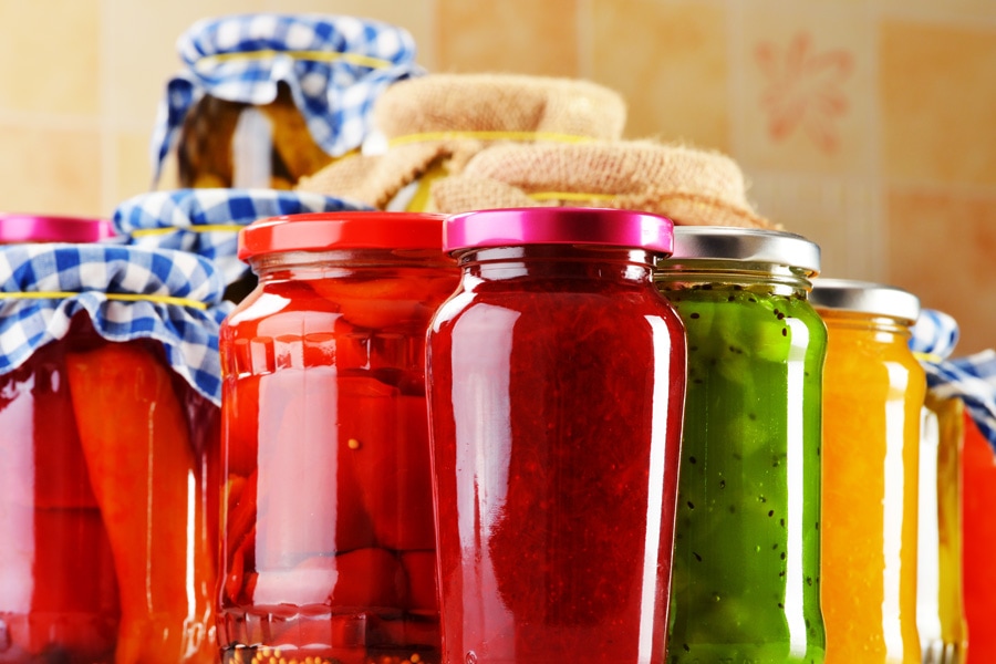Konserwowanie żywności Obraz nastroju: Grupa wypełnionych słoików do przetworów ozdobionych serwetkami z dżemem